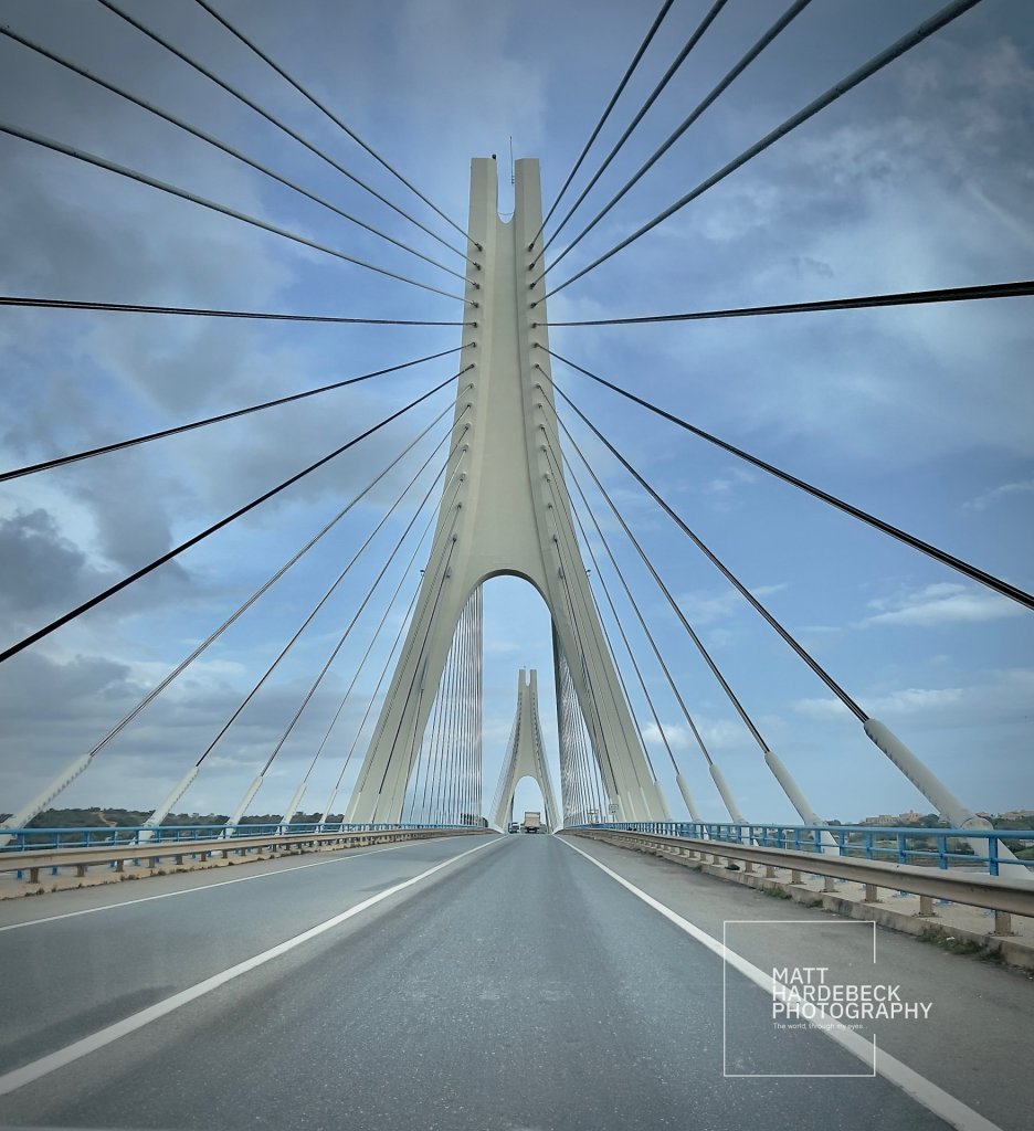 Modern cable-stayed bridge with soaring pylons and blue sky in Portugal.