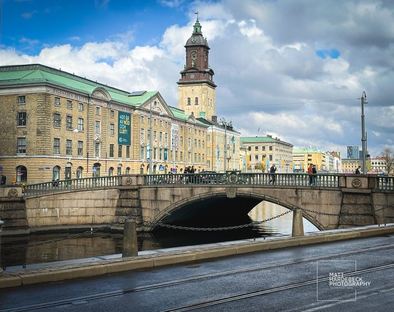 Historic stone bridge and cityscape in Gothenburg, Sweden, under a cloudy sky.