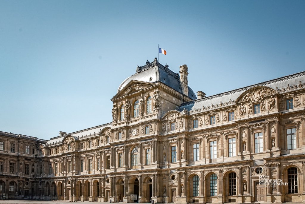 Cour Napoléon bathed in sunlight beneath a crisp Parisian sky.