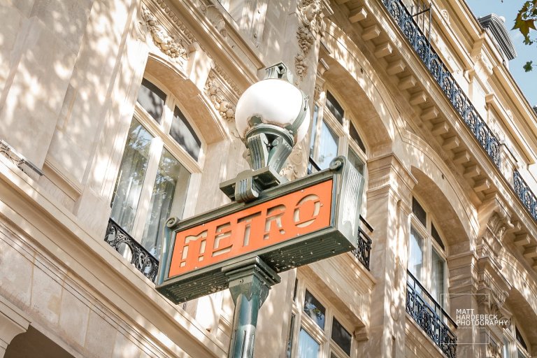 Vintage Paris Métro sign against classic Haussmannian architecture