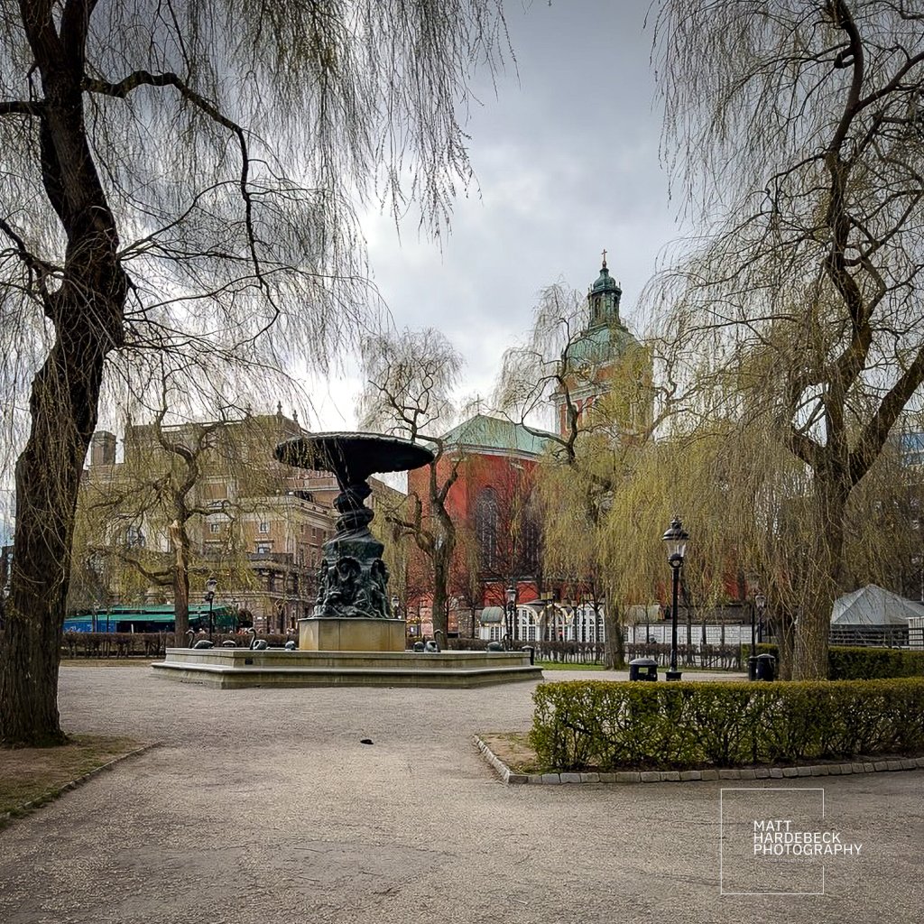 The Molin Fountain with weeping willows and the red tower of St. James’s Church.