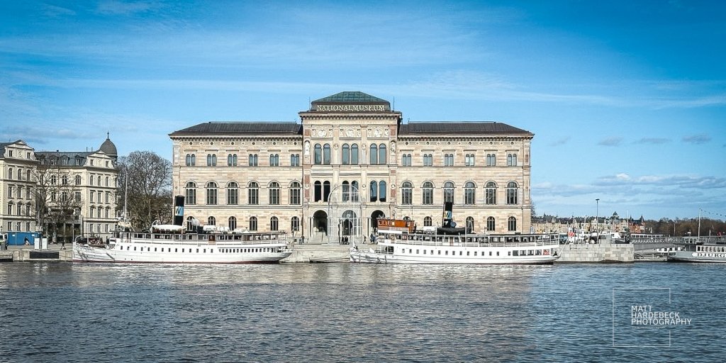 Stockholm’s Nationalmuseum viewed from across the water, with historic boats docked in front.
