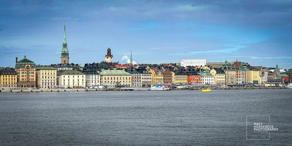Colorful buildings and church spires of Gamla Stan rising along the waterfront.
