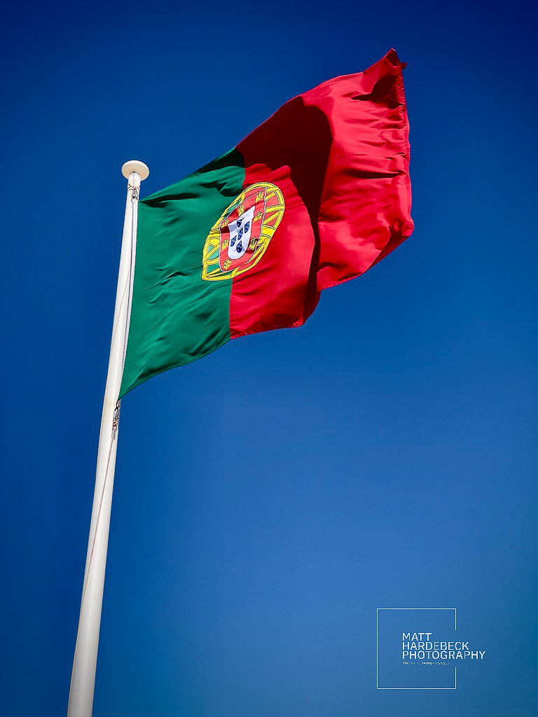 The flag of Portugal waving in a clear blue sky.