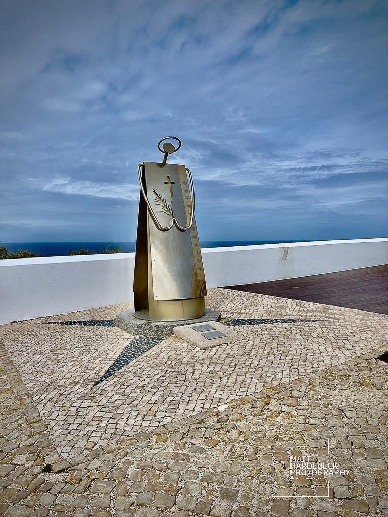 Modern monument with a palm frond and cross at Cabo de São Vicente, Portugal.