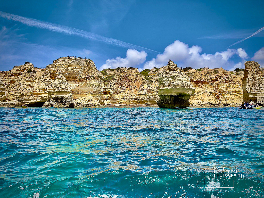 Golden limestone cliffs and turquoise waters along the Algarve coast in Portugal.