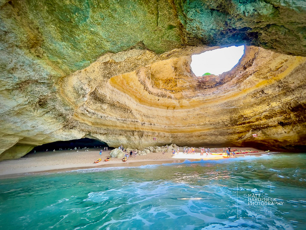 Interior of the Benagil Cave, with its iconic skylight illuminating the sandy beach below.