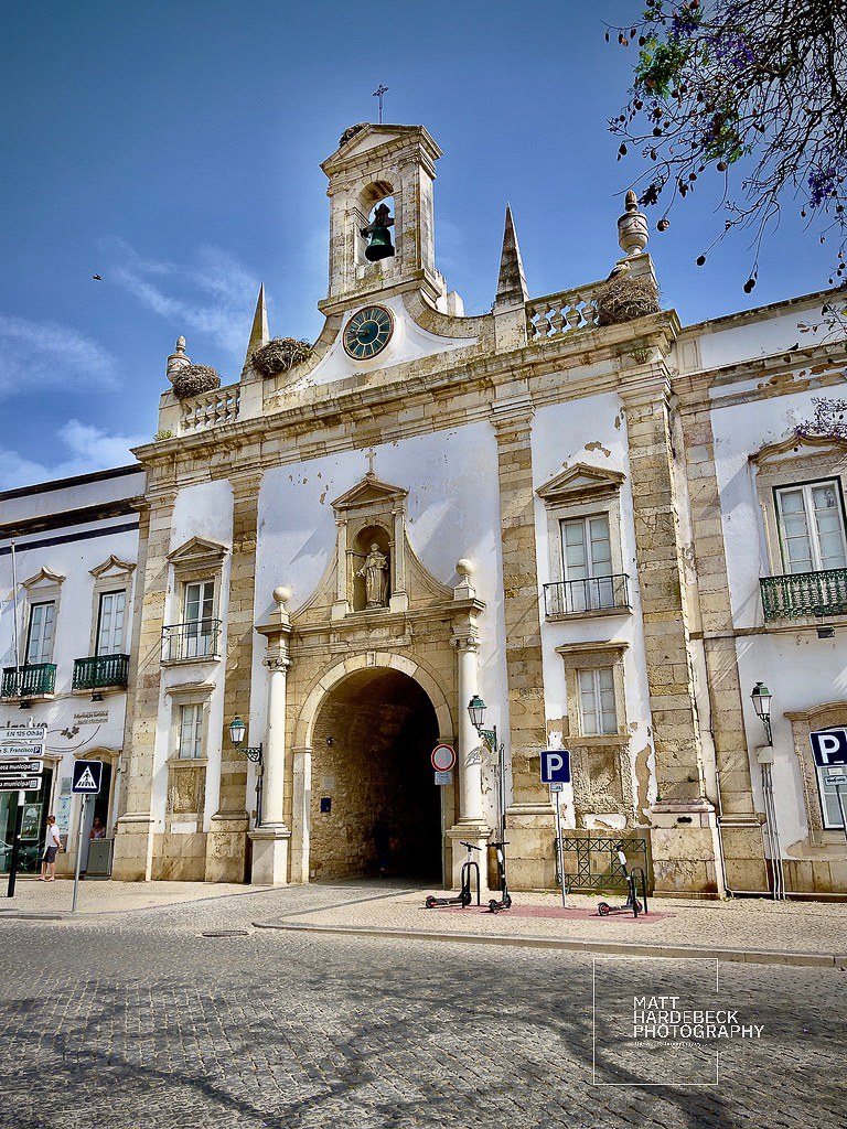 Stone archway entrance to Faro’s old town topped with a bell tower and clock.