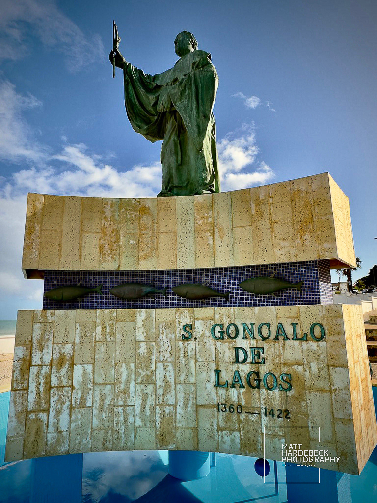 Statue of Saint Gonçalo de Lagos, 14th–15th century friar, set against a blue sky.