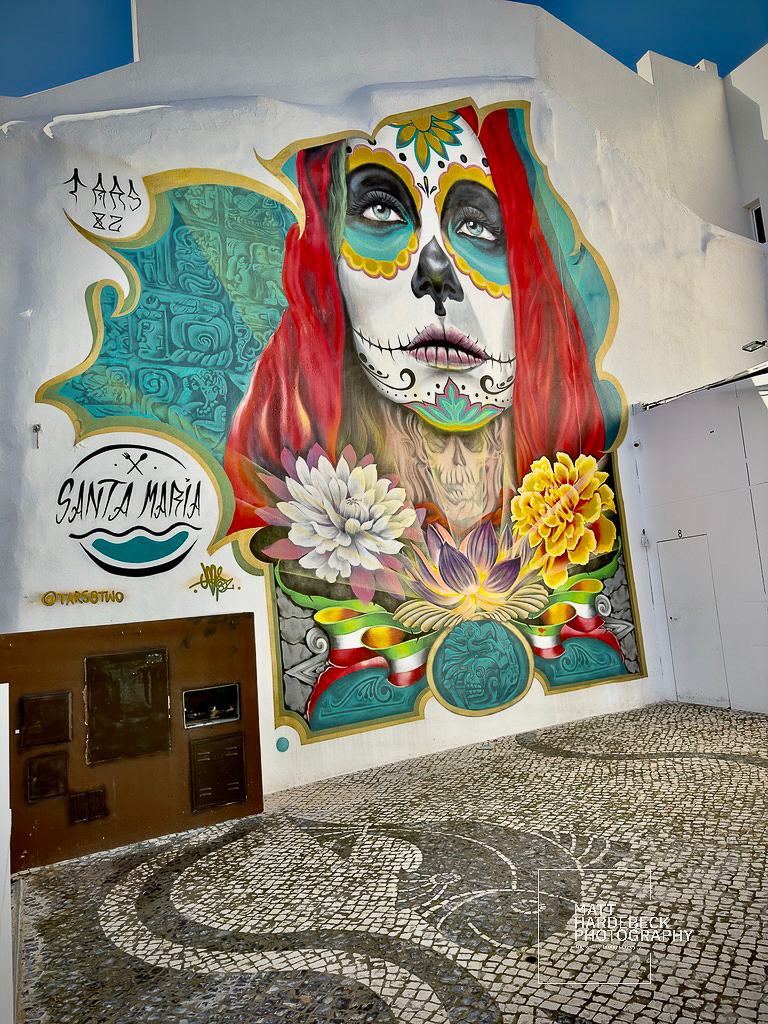 Colorful street mural of a woman with Day of the Dead face paint in Lagos, Portugal.