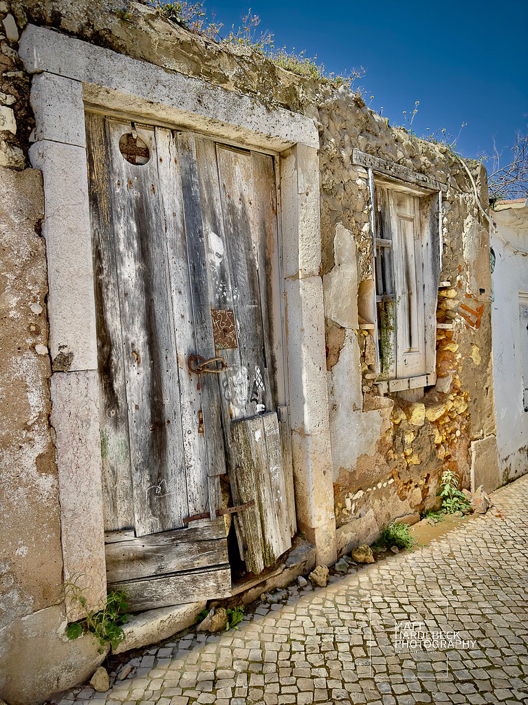 Weathered stone and wooden door of an abandoned building in Lagos, Portugal.