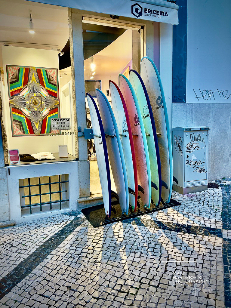 Surfboards in various colors lined up outside a surf and skate shop in Lagos, Portugal.
