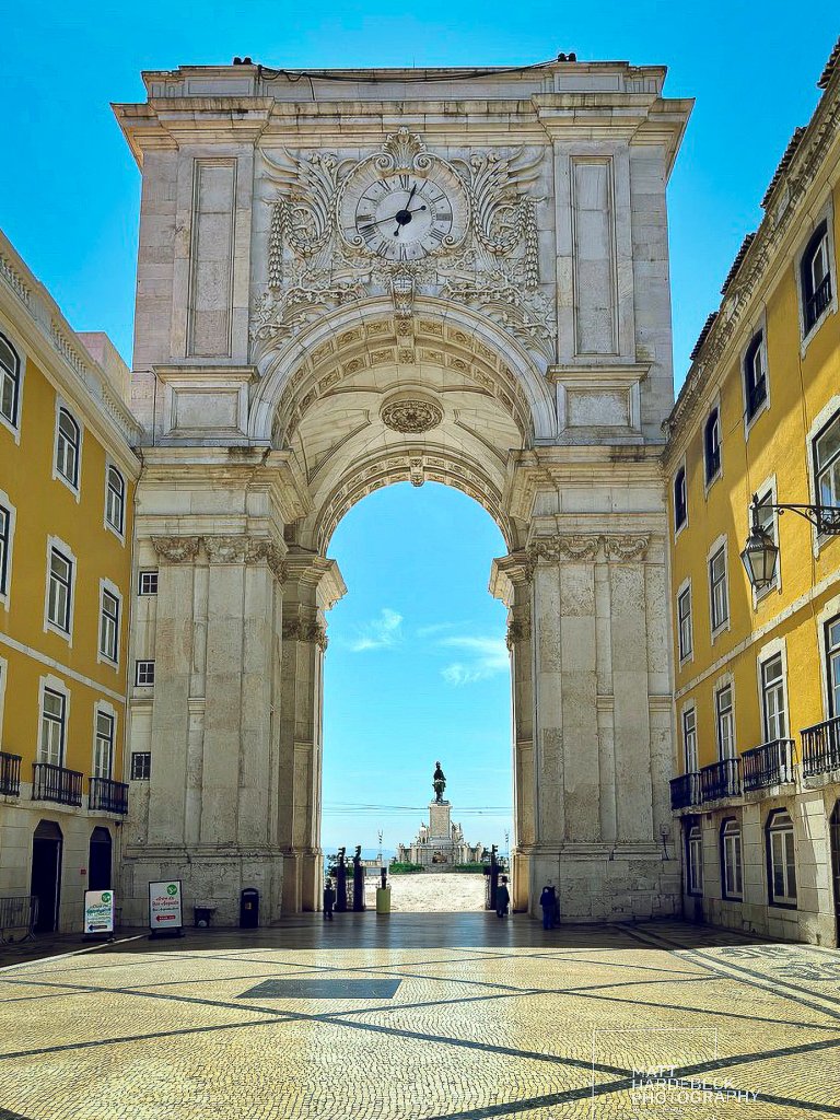 Arco da Rua Augusta in Lisbon, with its ornate stone carvings, clock, and view toward Praça do Comércio.