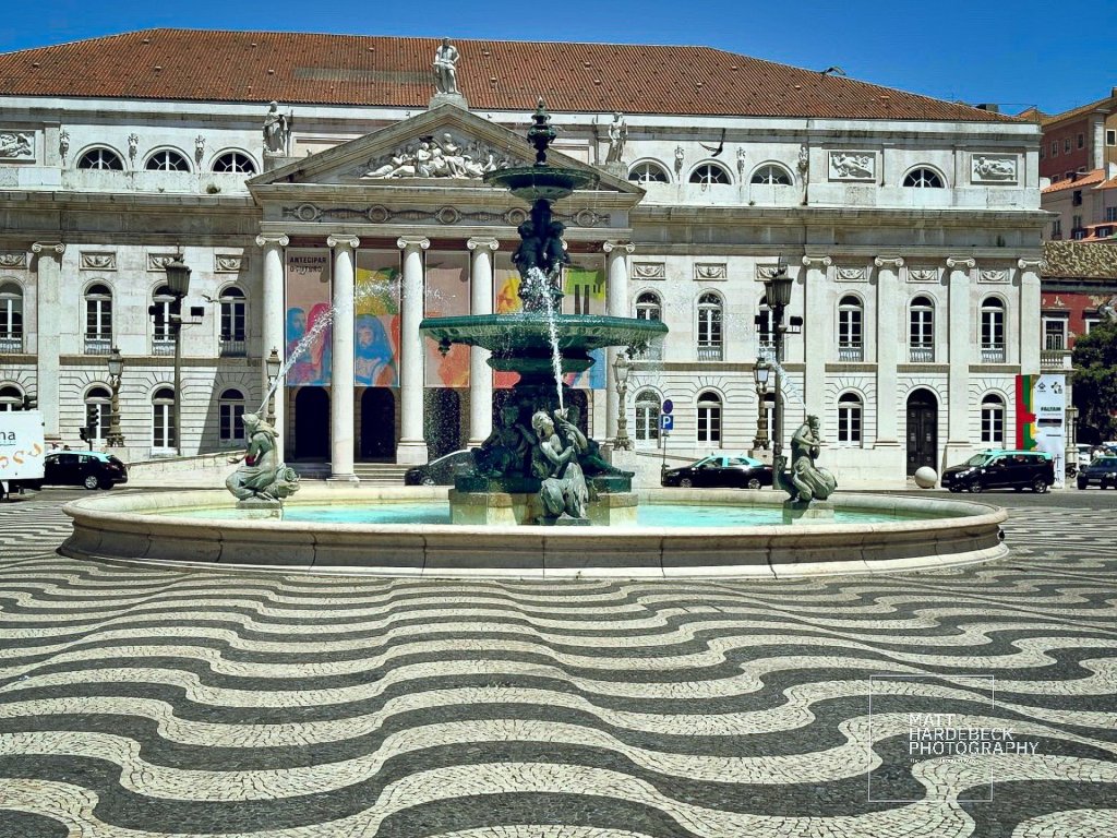 Ornate fountain in Rossio Square, Lisbon, with the National Theatre in the background.