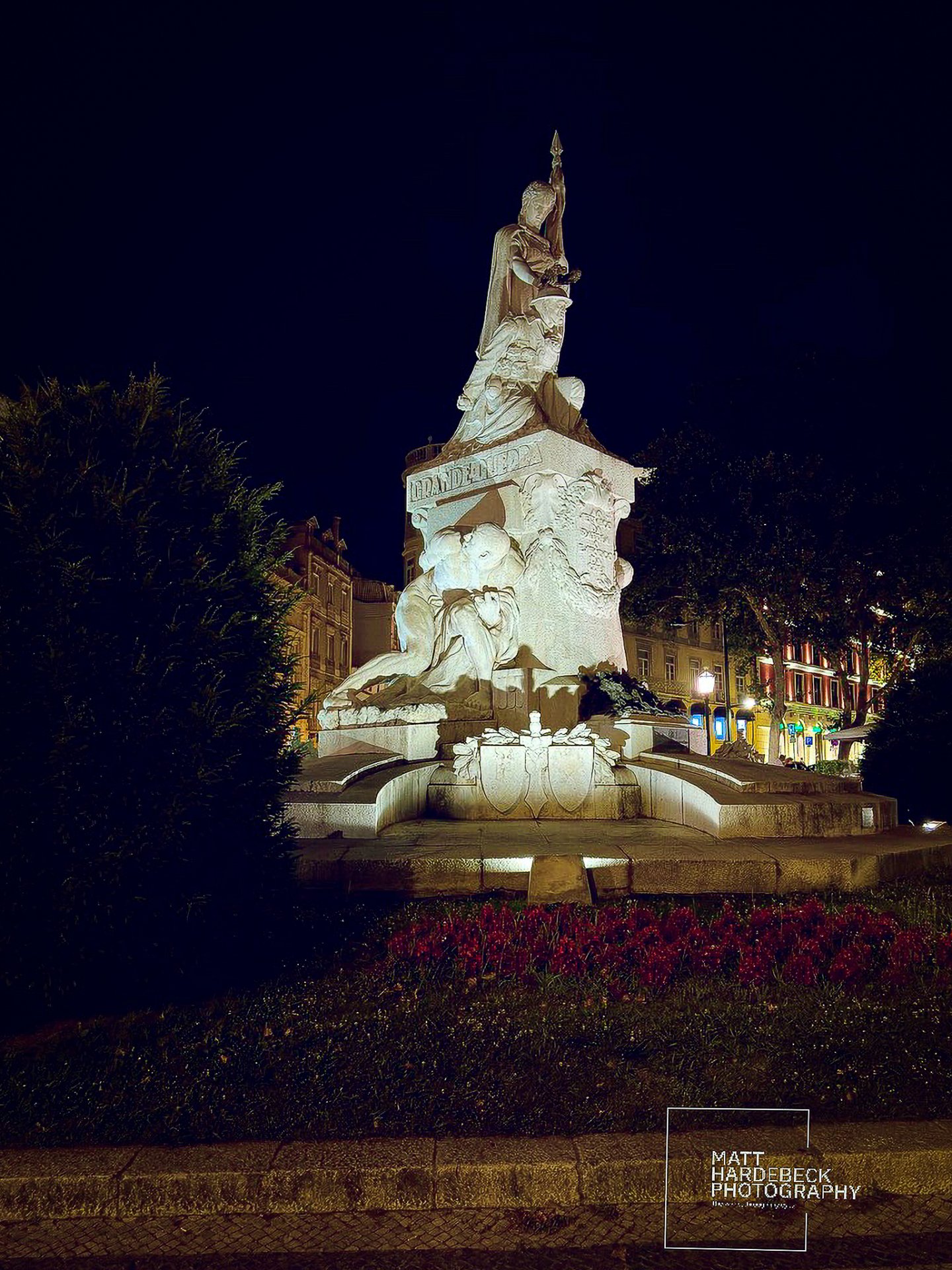 Night view of the Monument to the Restorers in Lisbon, illuminated against a dark sky.
