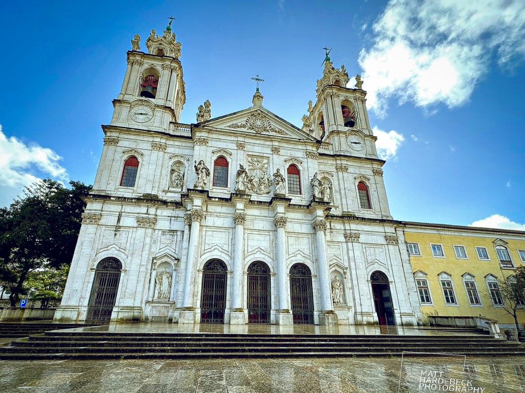 Baroque façade of the Basilica da Estrela against a blue sky with clouds.