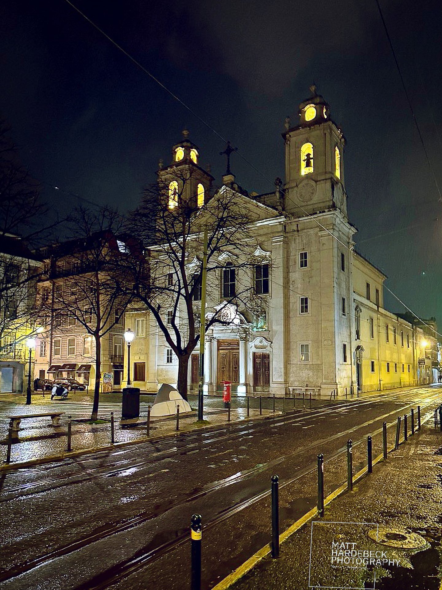 Illuminated twin towers of a Lisbon church on a rainy night.
