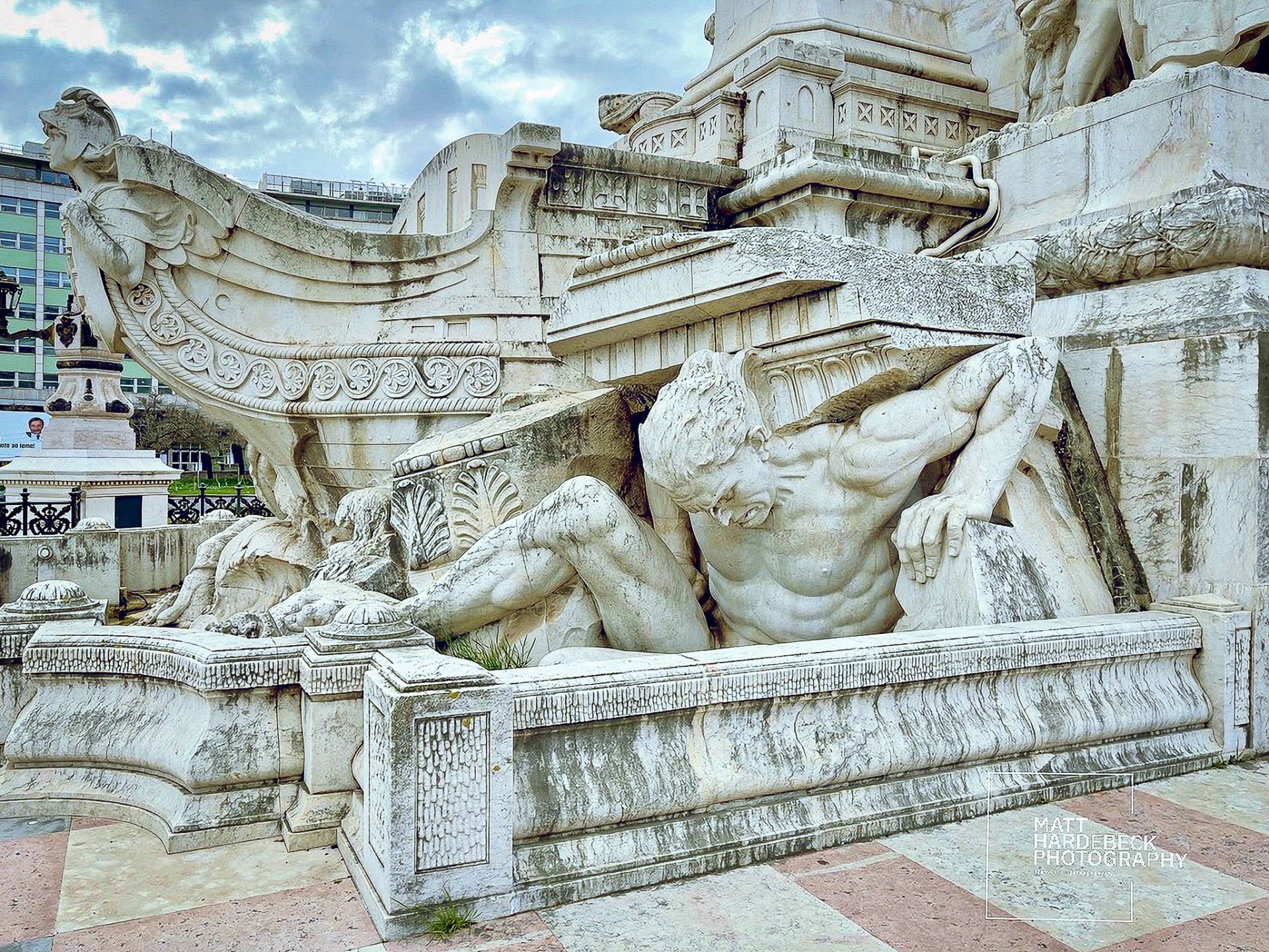 Sculpted figure straining under a ship’s bow at the base of the Marquis of Pombal monument in Lisbon.
