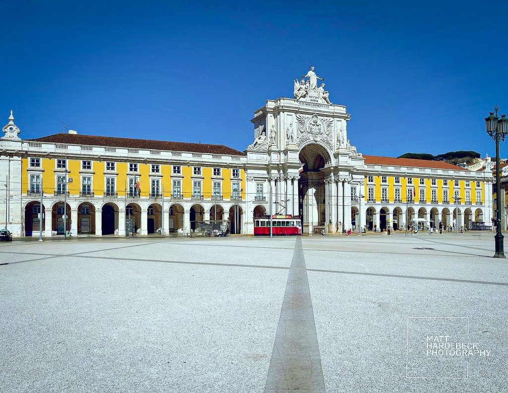 Close-up view of the Arco da Rua Augusta in Lisbon’s Praça do Comércio with a red tram passing underneath.