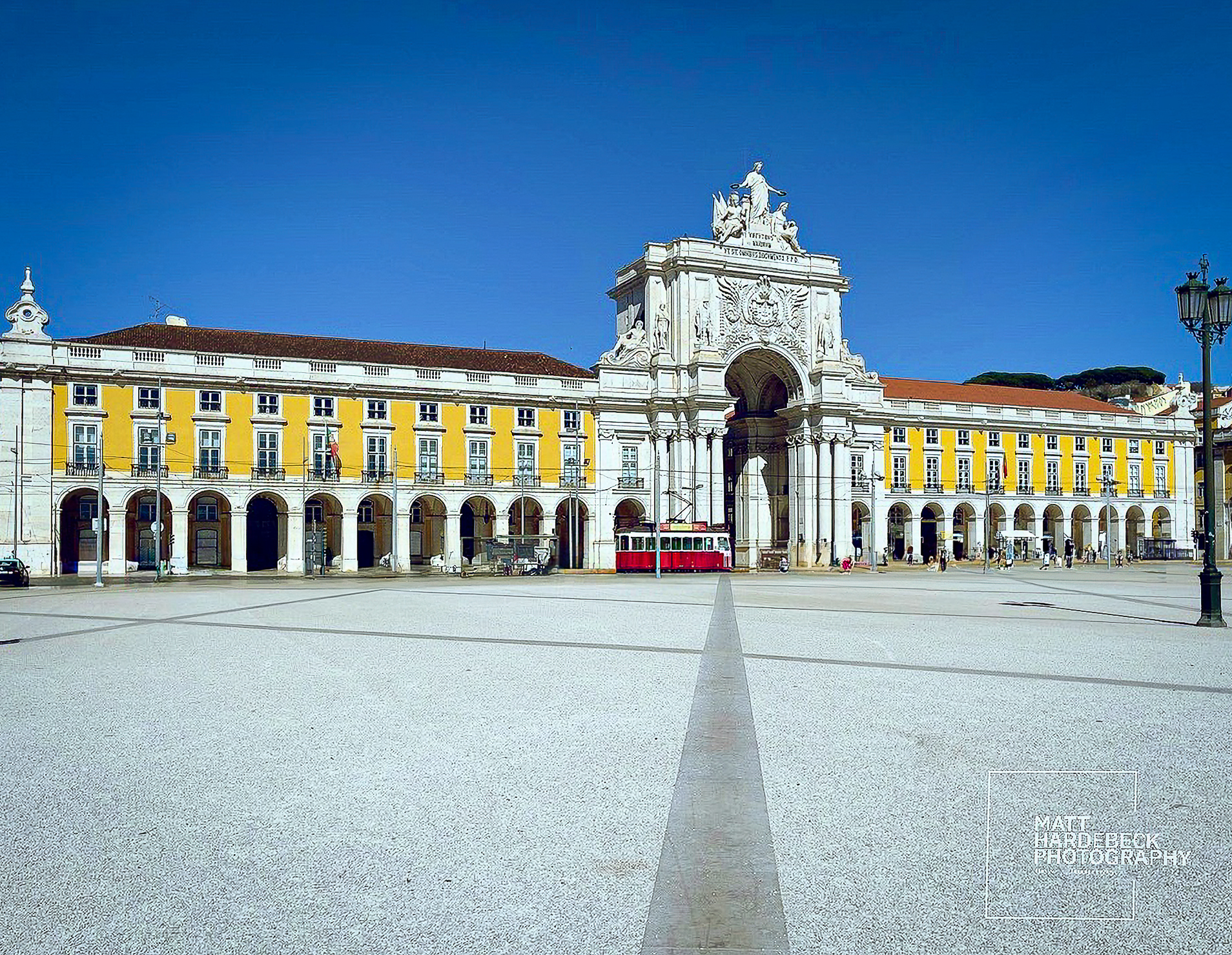Close-up view of the Arco da Rua Augusta in Lisbon’s Praça do Comércio with a red tram passing underneath.