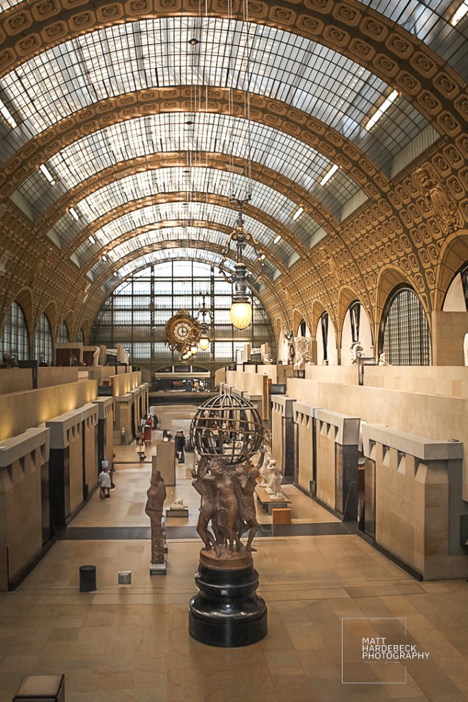 A wide-angle view of the main sculpture hall in the Musée d’Orsay, with classical statues and arched glass ceilings.