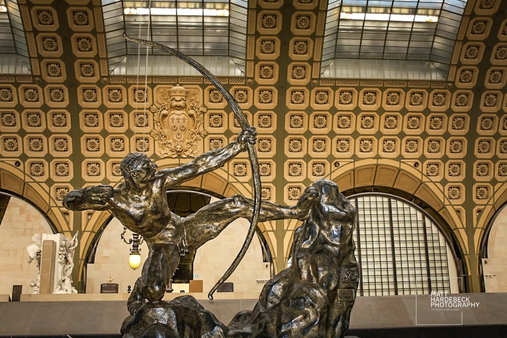 Bronze sculpture of Hercules drawing his bow by Antoine Bourdelle at the Musée d'Orsay, posed in dynamic tension beneath the museum’s ornate ceiling.