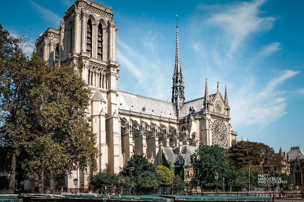 Side view of Notre Dame Cathedral with spire, roofline, and flying buttresses.
