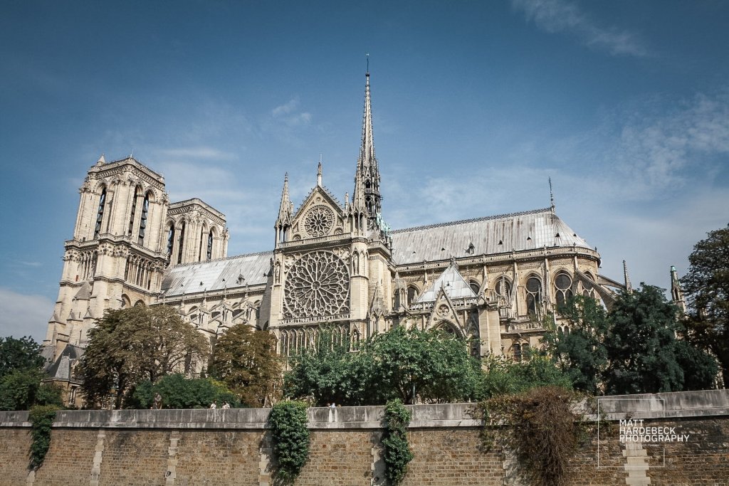 Side view of Notre-Dame Cathedral with spire, flying buttresses, and rose window.