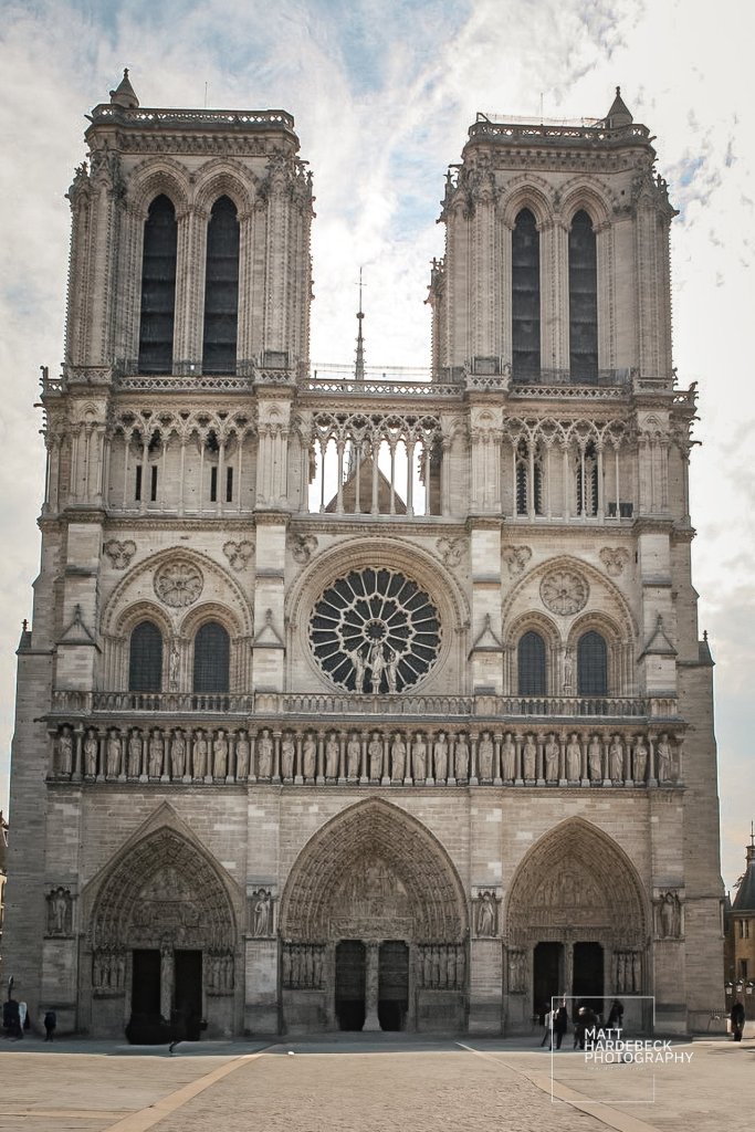 Front façade of Notre-Dame Cathedral in Paris, featuring the central rose window, twin bell towers, and sculpted portals beneath.