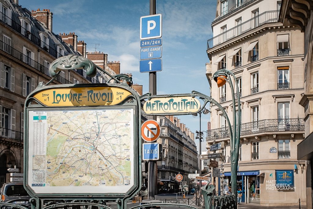 Entrance to the Louvre-Rivoli Paris Metro station with Art Nouveau sign and map.