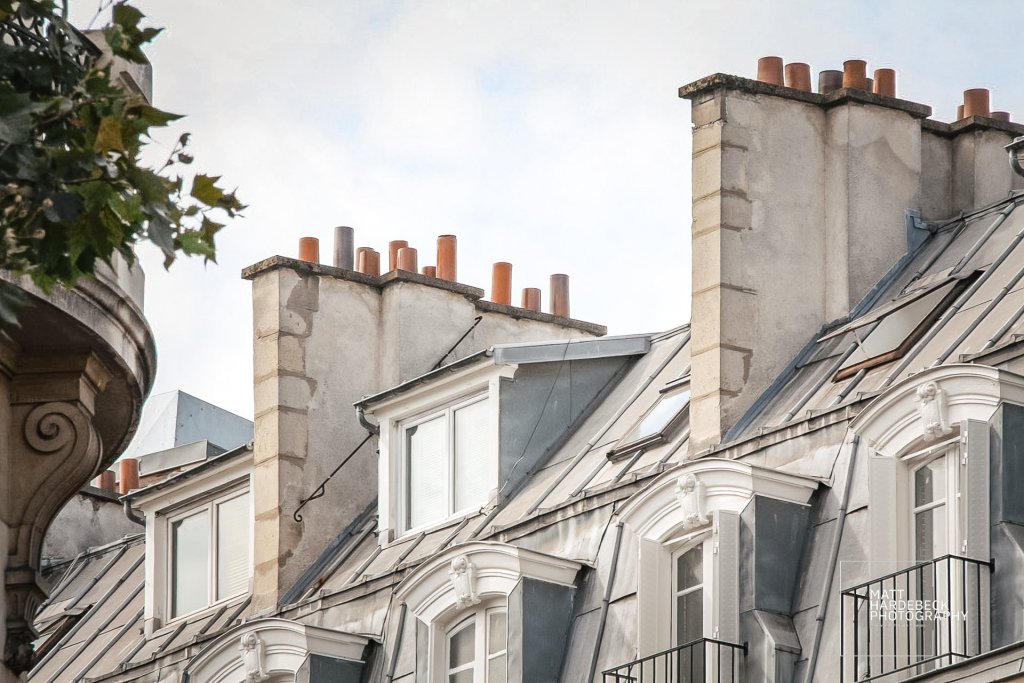 Close-up of Parisian rooftops with classic zinc roofs and chimney pots.