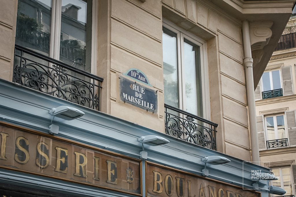 Close-up of Rue de Marseille street sign above a traditional Parisian bakery in the 10th arrondissement.