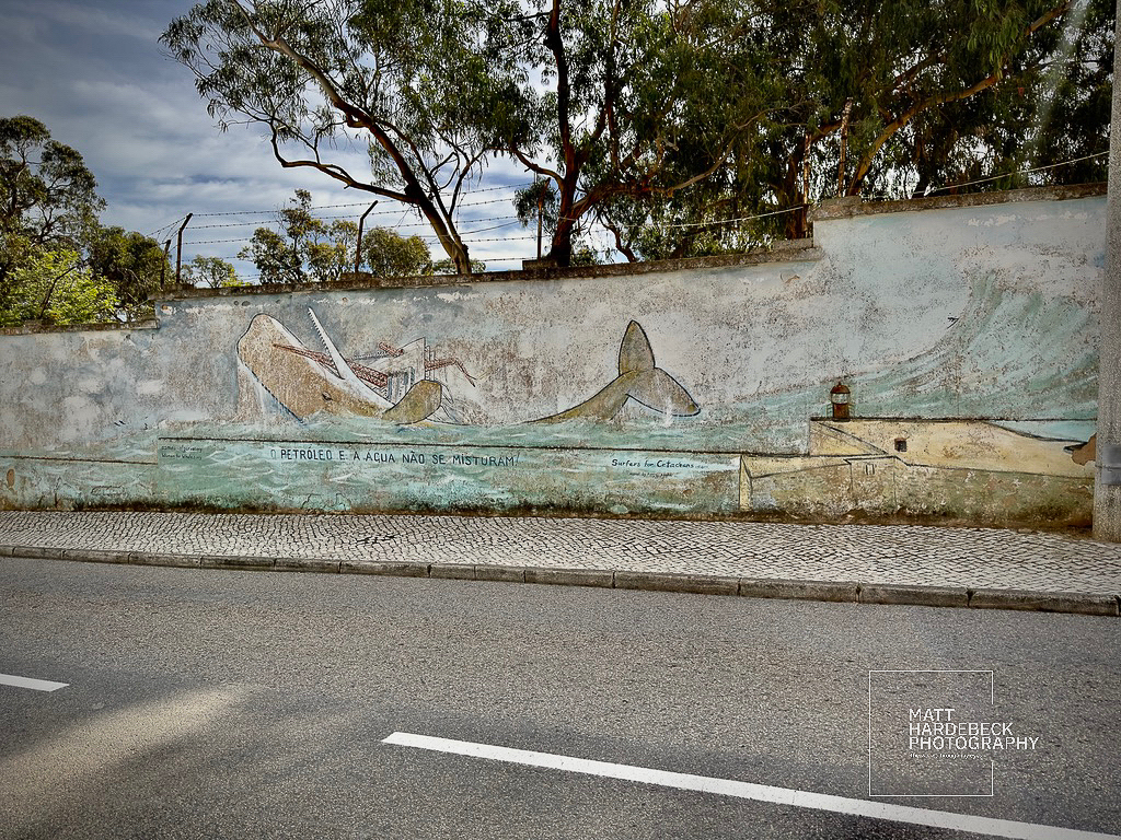 Mural in Lagos depicting a whale and lighthouse with the phrase “O petróleo e a água não se misturam.”