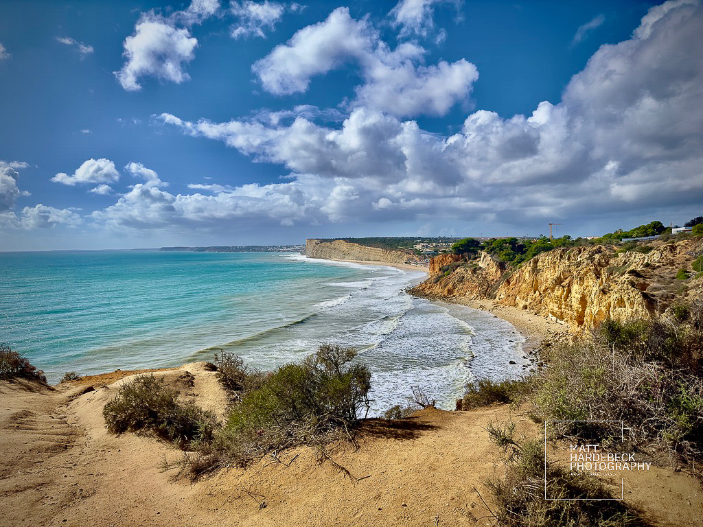 Expansive coastal view with golden cliffs and beach stretching toward the horizon.