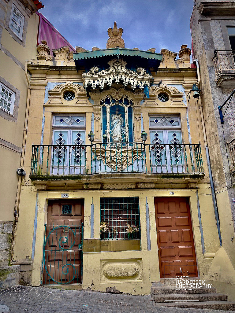 Ornate yellow and turquoise building façade with a religious statue in Porto.