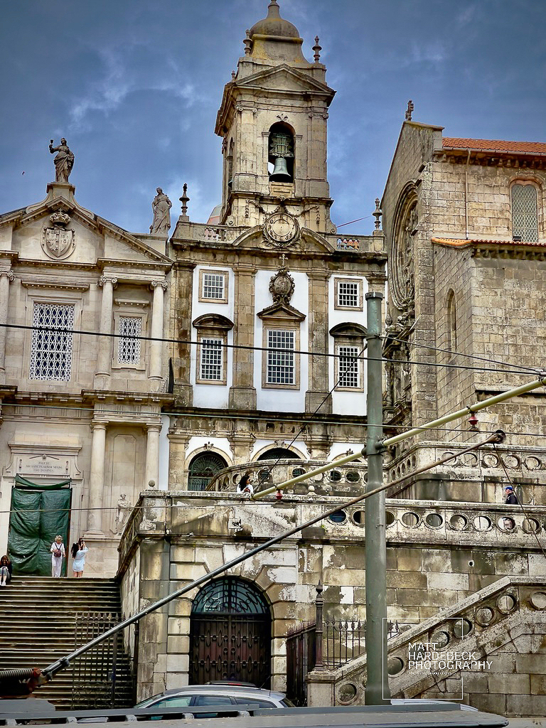 Baroque bell tower and ornate facade of Igreja de São Francisco in Porto, Portugal, with stone staircases leading upward.
