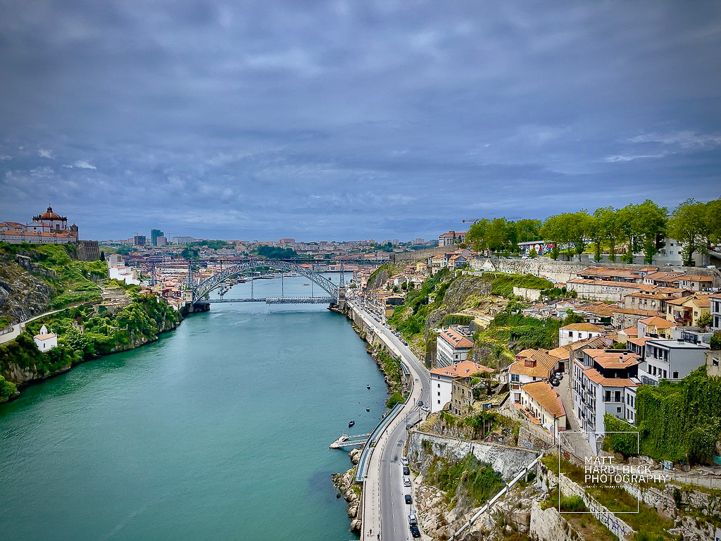 Panoramic view of Porto, Portugal, featuring the Dom Luís I Bridge spanning the Douro River under a dramatic sky.