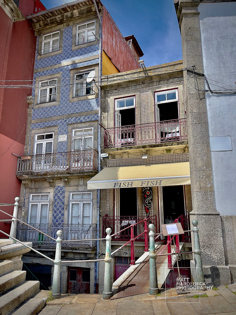 Colorful tiled buildings in Porto’s Ribeira district with a restaurant entrance labeled “Fish Fish.”