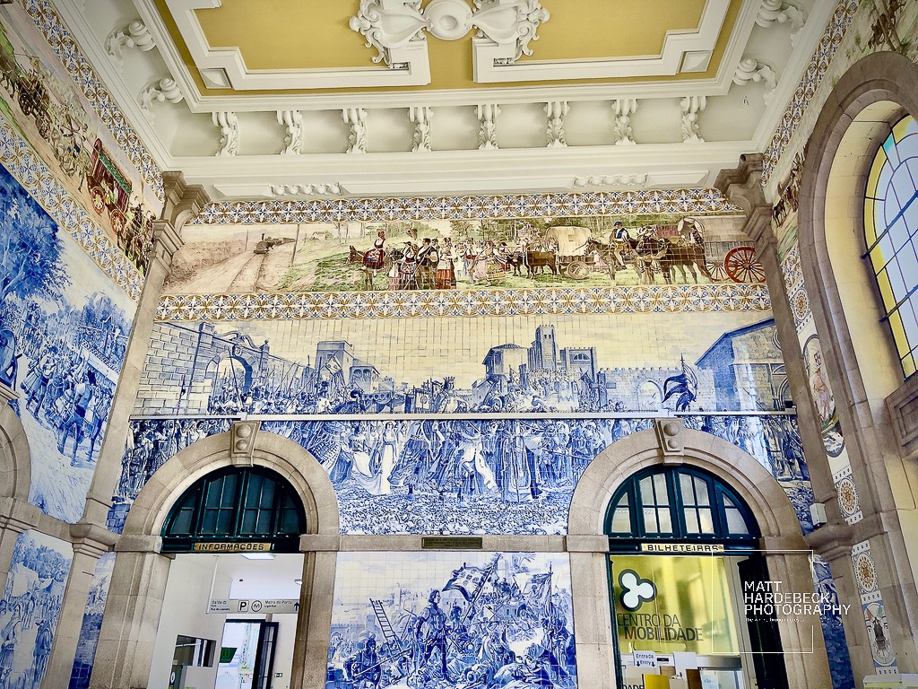 Ornate tile murals inside São Bento Railway Station depicting historical Portuguese scenes.