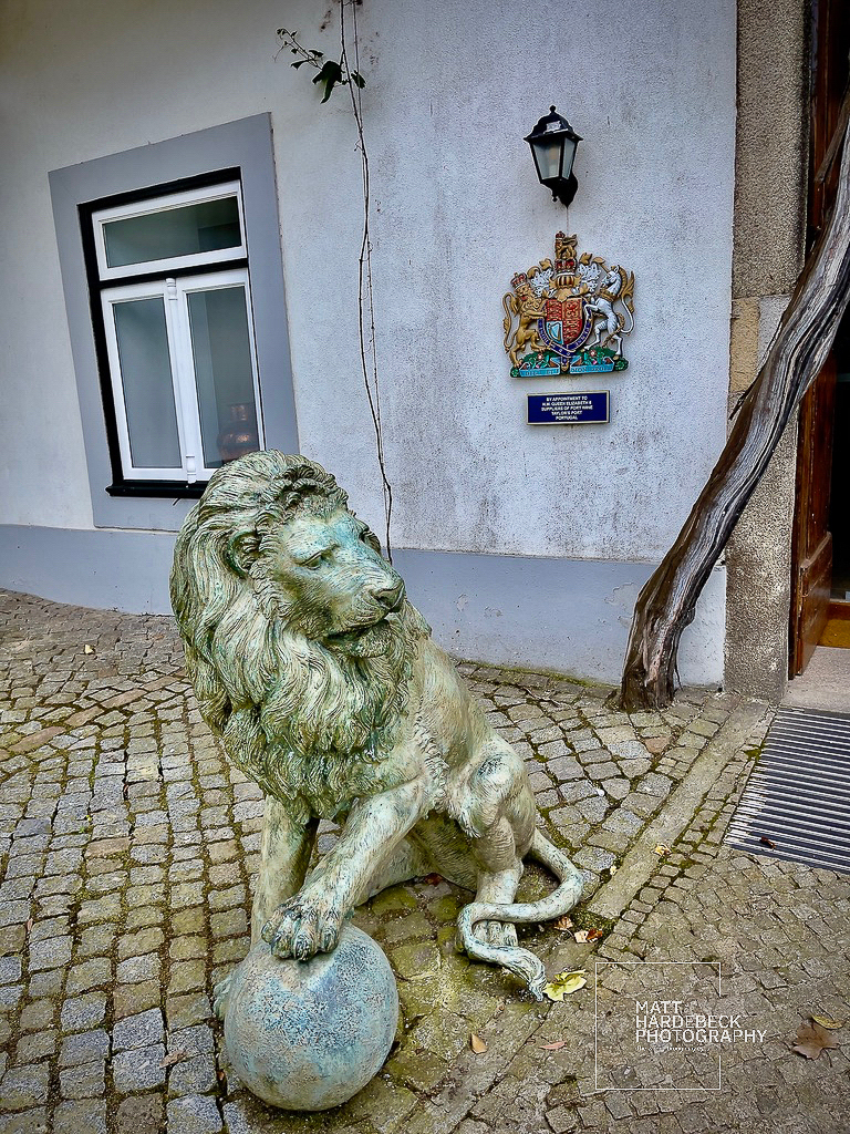 Stone lion statue with a paw resting on a ball outside Taylor’s port wine cellars in Porto, Portugal.