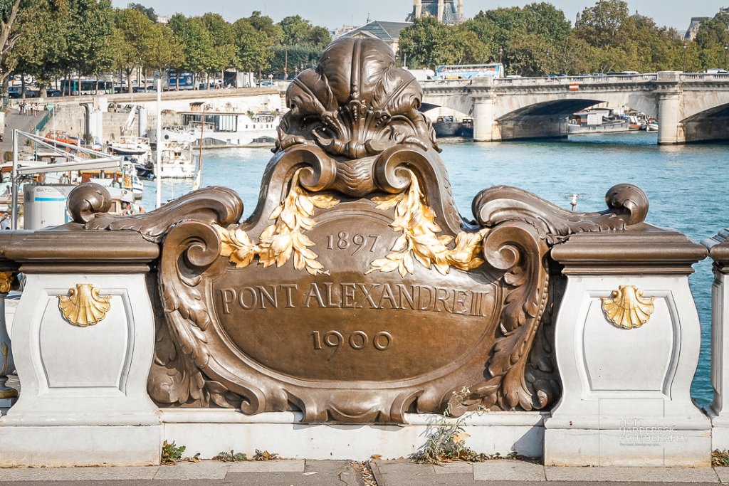 Decorative bronze plaque on Pont Alexandre III, inscribed with the bridge’s name and construction dates.