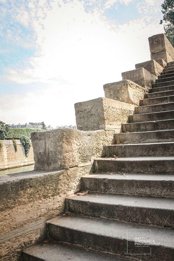 Stone staircase descending to the Seine’s edge with chunky limestone blocks and weathered steps.