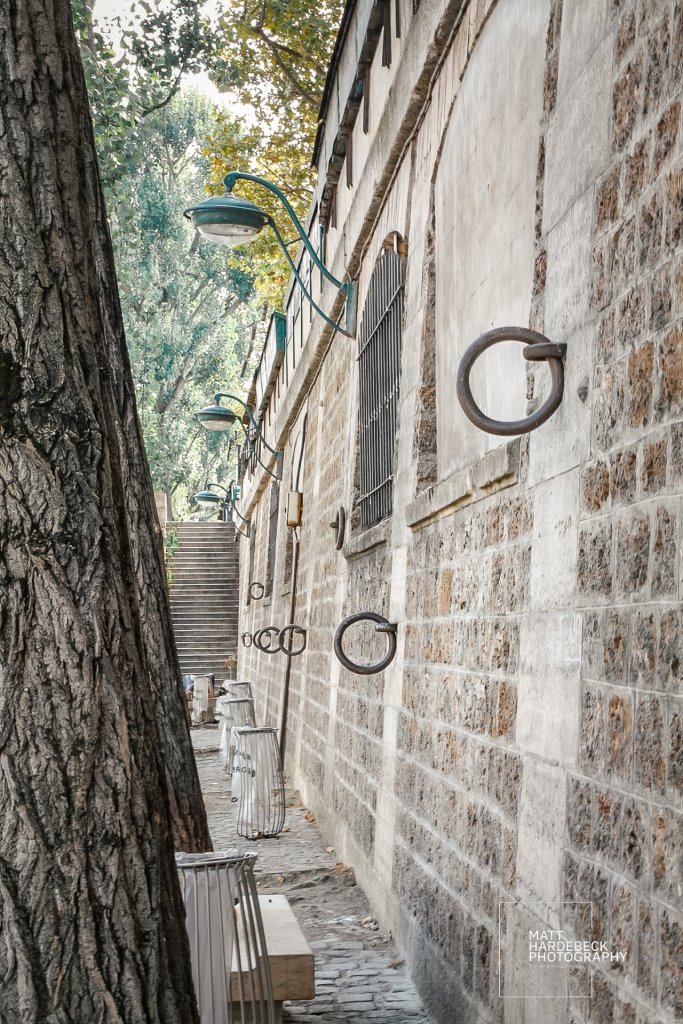 Stone wall along the Seine with large mooring rings and classic green lamps