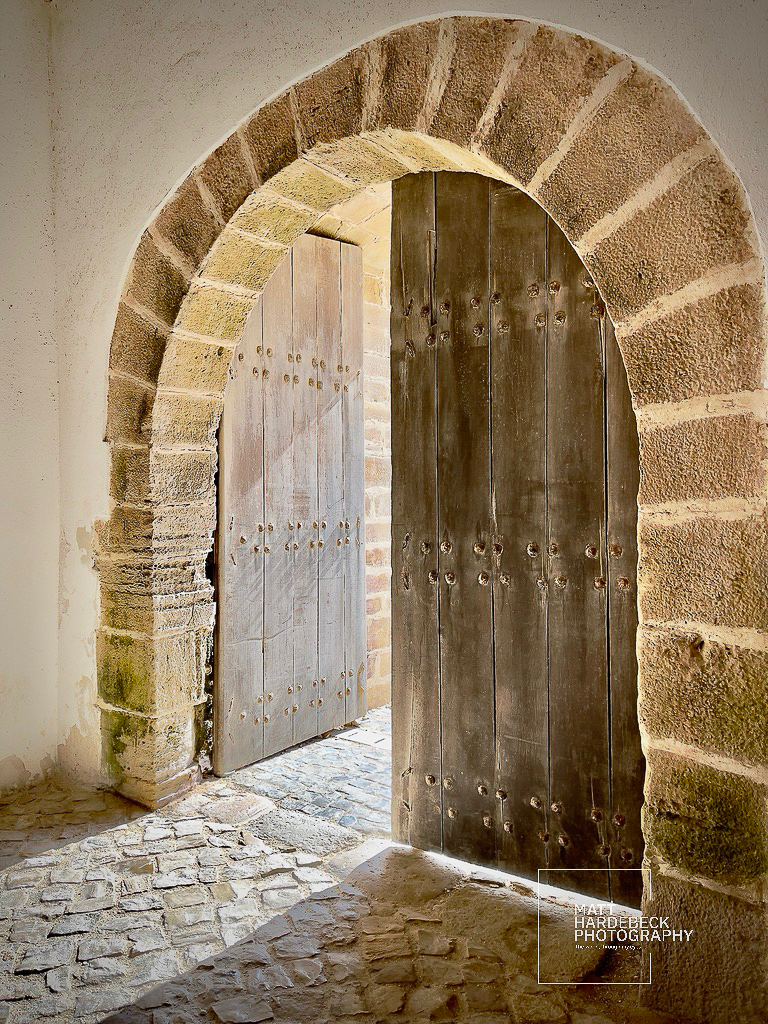 Wooden double doors set within a stone arch at Fortaleza de Sagres, Portugal.