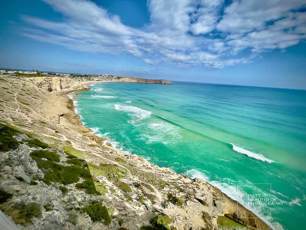Panoramic view of turquoise waters and rugged cliffs along the Algarve coast near Sagres, Portugal.