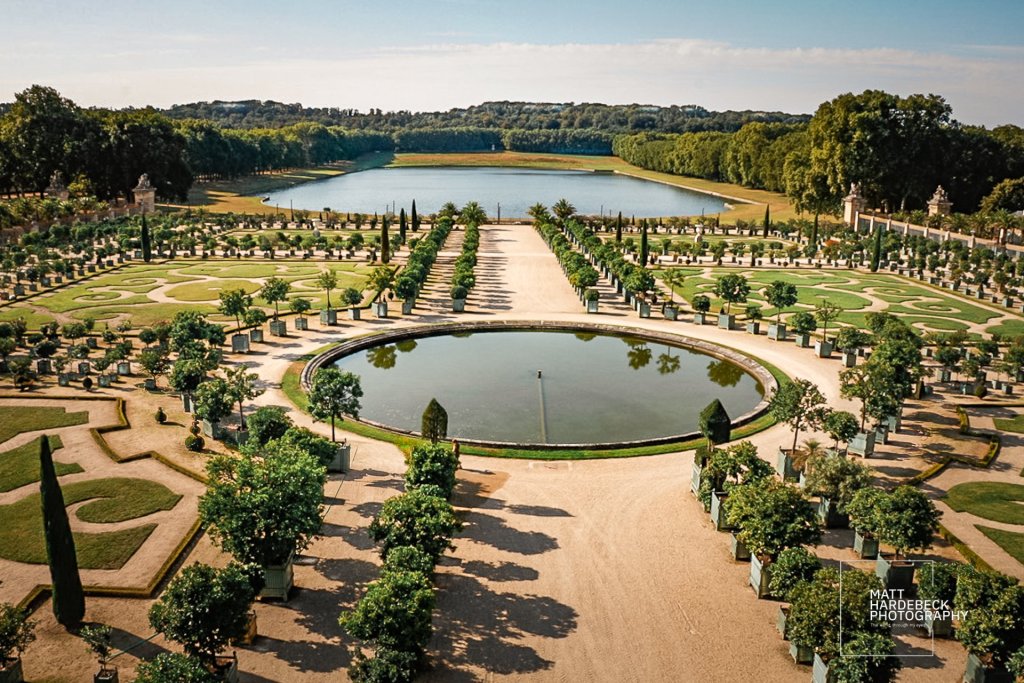 Fountain with gilded sculptures in the Versailles gardens, centered along a long grand canal.
