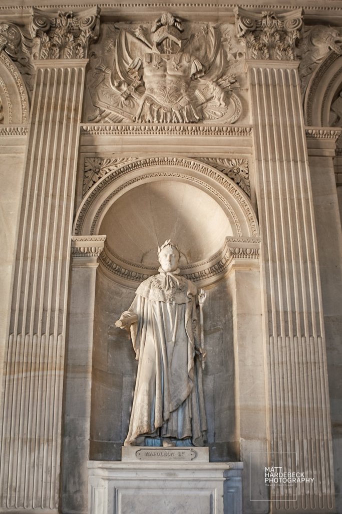 Marble statue of Napoleon I standing in an arched niche within the palace.