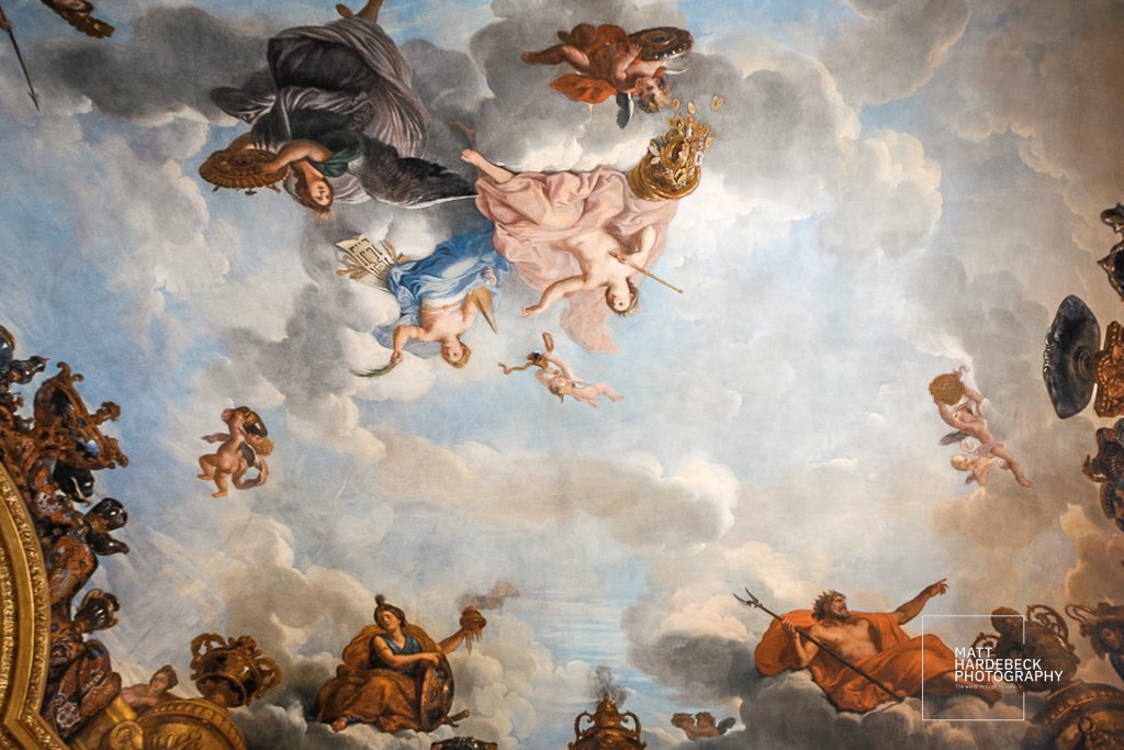 Ceiling fresco of mythological figures floating in clouds with vibrant colors and Baroque ornamentation.