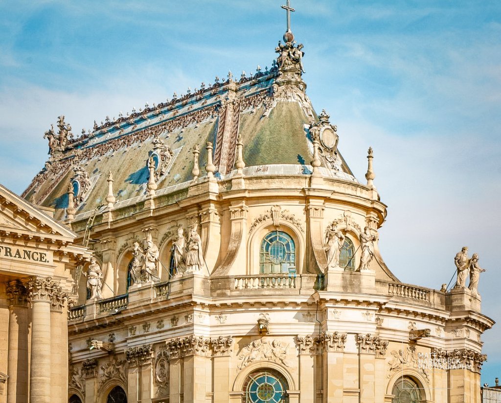 Close-up of the Chapel of Versailles with ornate rooftop statues and Baroque architectural details.