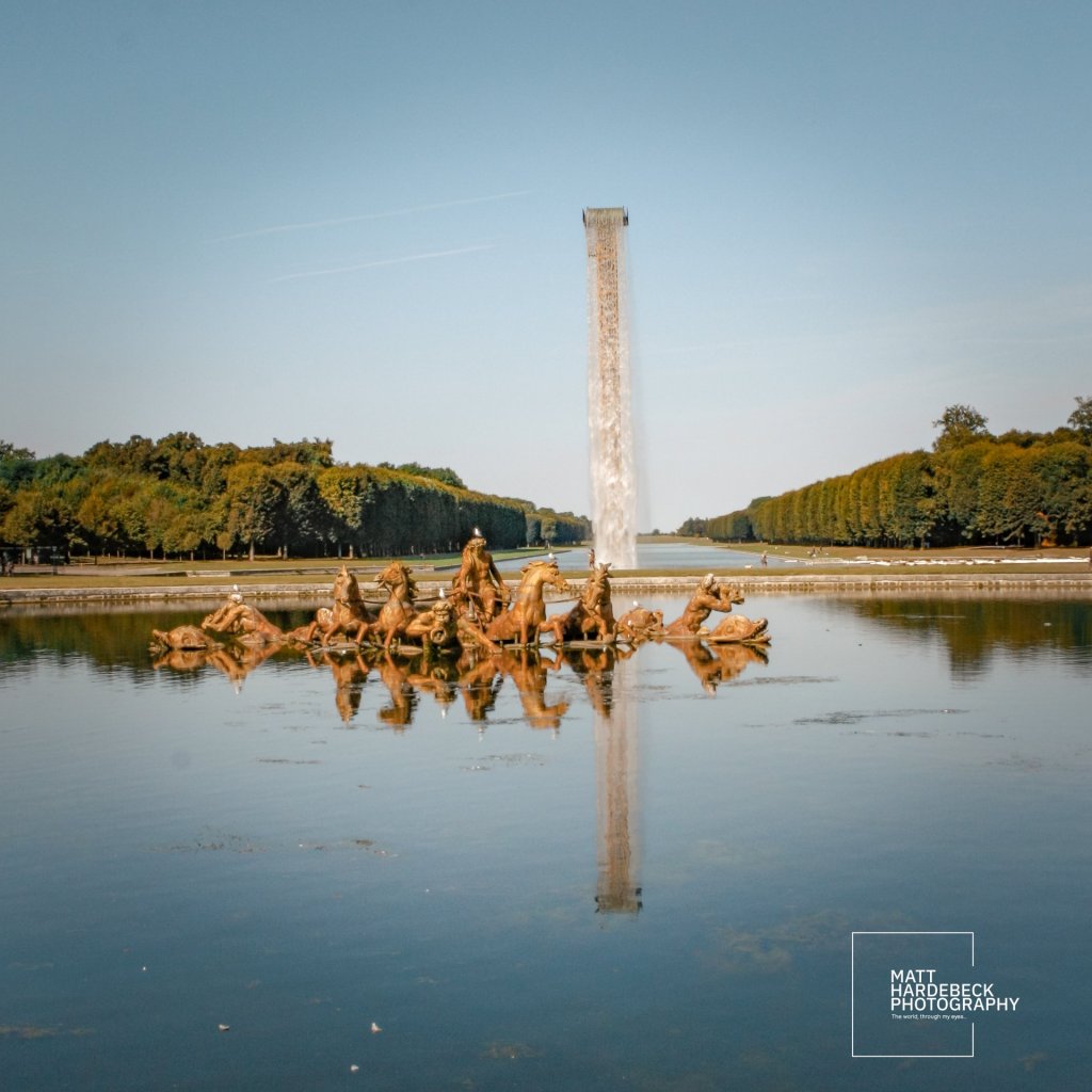 View of the Fountain of Apollo at the Palace of Versailles, with the bronze sculpture of Apollo’s chariot and a tall water jet rising in the Grand Canal beyond.